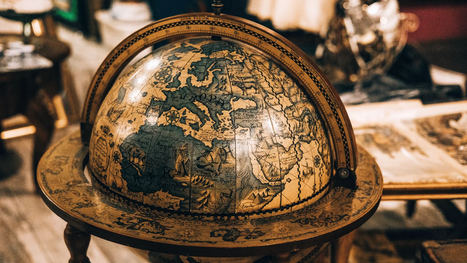 Antieke wereldbol op houten voet in een schemerige ruimte met oude kaarten