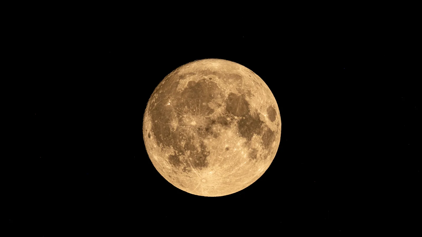 Volle maan in goudgeel licht, kraters en donkere vlakten scherp zichtbaar