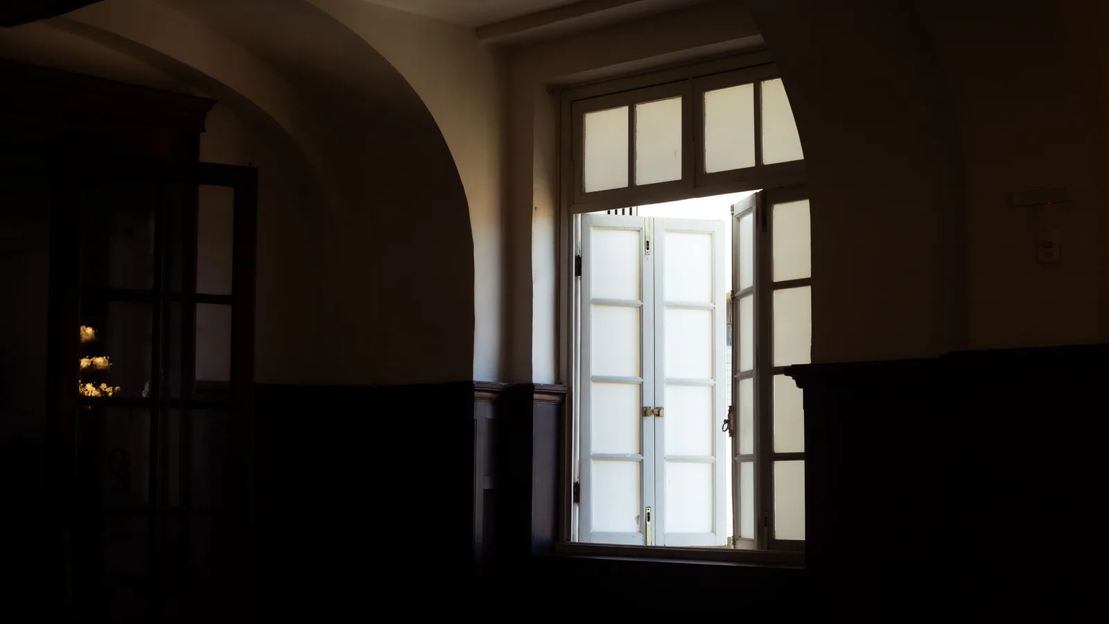 Lege donkere kamer met een openstaande deur waardoor daglicht naar binnen valt