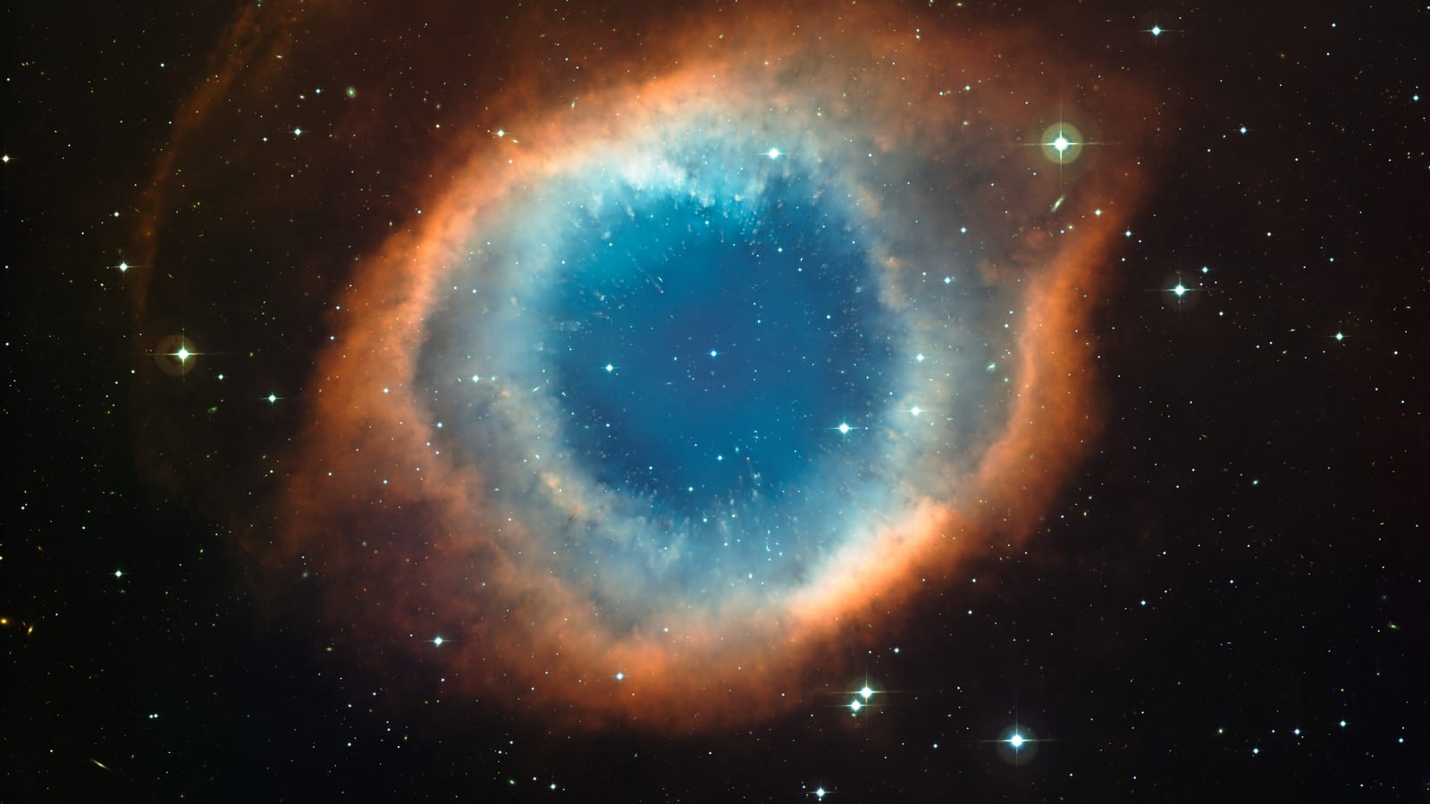 Ringvormige nevel met een blauwgroen binnenste en een oranjerode buitenrand, als een oog in een zwart sterrenveld